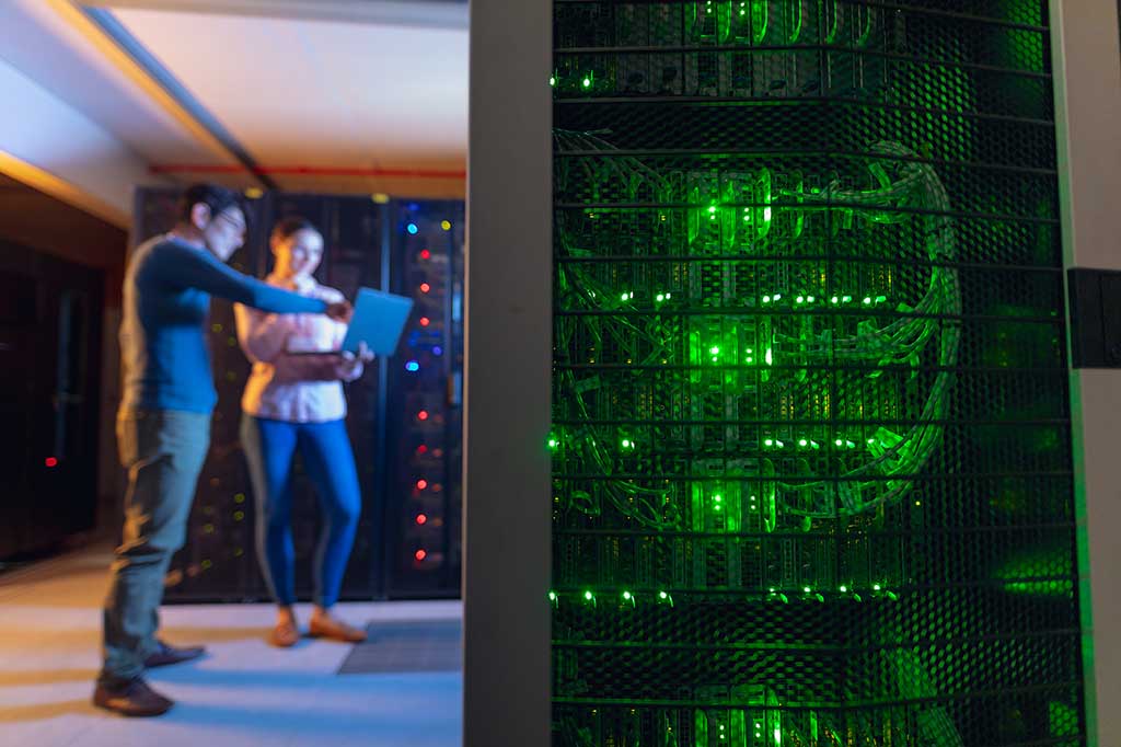 Two IT professionals inspecting web hosting servers in a secure data center environment.